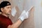 Man, repairman removes old wallpaper from the wall, replacing wallpaper