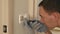Man repairs light switch and screws it to wall