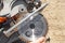 man replaces the saw blade of an electric miter saw for woodworking. Repair and maintenance of power tools.