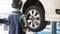 Man Replacing Car Wheel with Pneumatic Impact Wrench at Repair Service Station