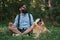 Man resting on the grass sitting crossed legs with his dog