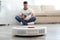 Man resting while robotic vacuum cleaner doing his work