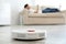 Man resting on sofa while robotic vacuum cleaner doing his work
