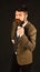 Man in retro smart suit and vest on brown background. Businessman with confused face adjusts bow tie