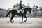 Man rider and black stallion horse trotting during equestrian dressage competition in summer