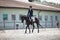 Man rider and black stallion horse trotting fast during equestrian dressage competition in summer