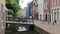 Man rides his bicycles along the street beside a canal running through a town