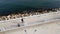 A man rides a longboard on a seaside promenade, seen from a drone