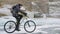 Man is riding bicycle near the ice grotto. The rock with ice caves and icicles is very beautiful. The cyclist is dressed