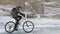 Man is riding bicycle near the ice grotto. The rock with ice caves and icicles is very beautiful. The cyclist is dressed