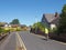 A man riding a bicycle wearing a reflective vest down a street of typical english suburban bungalows in formby merseyside