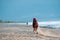 Man riding on a brown galloping horse along Ayia Erini beach against a rough sea