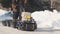 Man riding on crawler mini snowmobile with a trailer and a passenger on a winter road