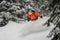 Man riding down the hill between trees making snow splash