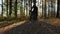 A man is riding his mountain bike through an autumnal forest and brakes sharply with a skid. Behind him, the sun shines