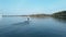 Man riding on a hydrofoil surfboard and falling in large blue lake on sunny day