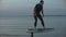 Man riding on a hydrofoil surfboard on large blue lake at the pink sunset