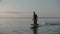 Man riding a hydrofoil surfboard on large lake at warm sunset sitting on knees