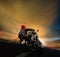 Man riding motorcycle on asphalt highway against sunset sky