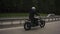 Man riding scrambler motorbike on the highway through the autumn forest