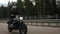 Man riding scrambler motorbike on the highway through the forest, side view
