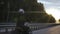 Man riding scrambler motorbike on the highway through the forrest at the sunset