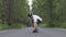 Man riding on skate board on asphalt puddles road in green summer rain forest. Skater ride cruise longboard on road