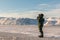 Man with a rifle and binoculars looks out on the horizon in arctic landscape at Svalbard