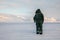 Man with a rifle looks out on the horizon in arctic landscape at Svalbard