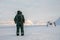 Man with a rifle looks out on the horizon in arctic landscape at Svalbard