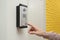 Man ringing intercom with camera in entryway, closeup