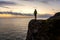 Man on a Rocky Ocean Coast during Sunset