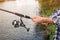 Man with rod fishing at riverside, focus on hands