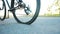 A man rolls a bicycle with a punctured wheel on the asphalt against the backdrop of the summer sun, close-up. Slow