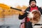 Man rowing a canoe with his spaniel dog, sunny autumn weather.