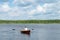 Man rowing in a wooden boat, floating on a lake on a sunny day, active weekend, rear view