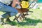 Man in rubber boots starts a tractor motoblock  for plowing fields