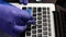 A man in rubber gloves is cleaning his laptop. Dip a cotton swab in a cleaning agent and clean the laptop keyboard. Protection of