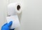 A man in rubber gloves tears off a piece of toilet paper roll of toilet paper on a white background. Disinfection in public places