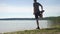 Man runner stretching at lake. Running man stop for stretching his body. Daily workout in attractive nature