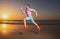 Man running on the beach at sunset. Guy runner jogger running. Dynamic jumping movement. Sport jump.