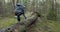 Man running on forest trail and jump over old fallen tree. slow motion