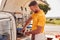 Man Running Independent Mobile Coffee Shop Preparing Drink Standing Outdoors Next To Van