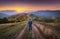 Man on the rural dirt road on the hill looking on mountain in fog