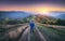 Man on the rural dirt road on the hill looking on mountain in fog