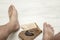 Man`s bare feet on and tar soap with and a washcloth on wooden board