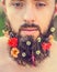 Man\'s face with a beard with flowers in his beard natural background, close up