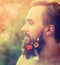 Man\'s face in profile with a beard with flowers his beard on natural background with bokeh