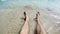 Man`s feet washed by ocean waves and buries them in the sand. Close-up of a man`s foot lying on the beach