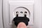 A man`s  finger plugging a plug into a wall socket